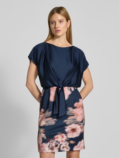 Vrouwenmodel draagt Knielanges Cocktailkleid met Knotendetail van SWING, donkerblauw met bloemenprint, materiaalmix met stretch, recht model, knielengte, ronde hals, ruglengte 92 cm, borstwijdte 41 cm, mouwlengte 13 cm, vooraanzicht busteshot.