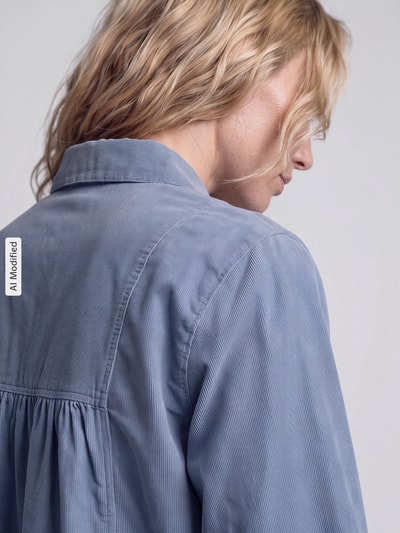 Frauenmodel trägt Regular Fit Langarmbluse aus reiner Baumwolle von Marc O'Polo DENIM, hellblau, feine Struktur, Nahaufnahme Rückansicht, KI-modifiziertes Bild.
