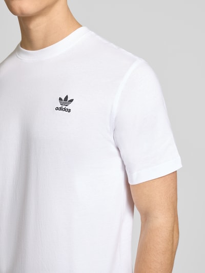 Männermodel trägt weißes T-Shirt mit Label-Stitching von adidas Originals, reine Baumwolle, Regular Fit, Nahaufnahme Oberkörper.