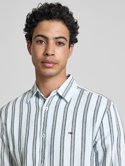 Männermodel trägt Regular Fit Freizeithemd aus Leinen-Baumwoll-Mix von Tommy Jeans, Mehrfarbig, Gestreift, Logo-Schriftzug, Nahaufnahme Oberkörper.