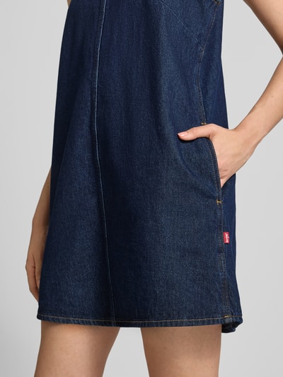 Frauenmodel trägt A-Linien Freizeitkleid aus reiner Baumwolle von Levi's®, dunkles Jeansblau, strukturierte Oberfläche, Nahaufnahme Oberkörper.