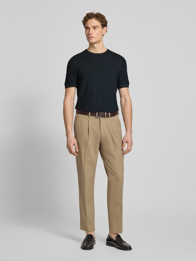 Männermodel trägt T-Shirt aus Baumwoll-Leinen-Mix von Profuomo in Schwarz, kombiniert mit beigen Hosen, Ganzkörperansicht von vorne. Slim Fit, Rundhalsausschnitt, Rückenlänge 70 cm bei Größe M.