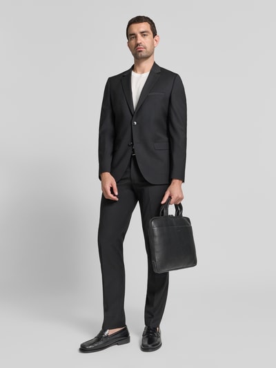 Männermodel trägt Laptoptasche aus Leder mit Tragehenkel Modell 'Cardona Samu' von JOOP!, schwarze Farbe, Ganzkörperansicht von vorne.