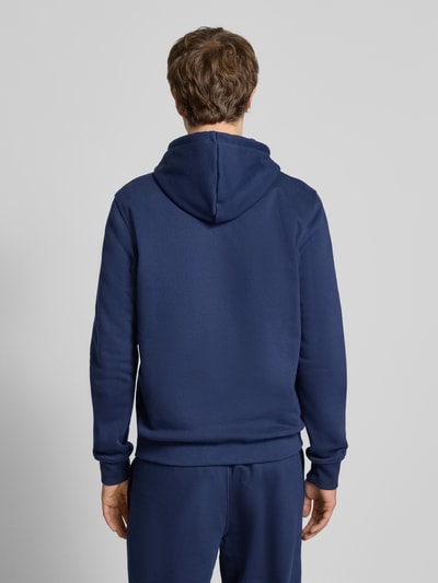 Męski model nosi Hoodie mit Kapuze od adidas Originals, bawełniana mieszanka, luźny krój, kolor granatowy, widok całej sylwetki z tyłu.