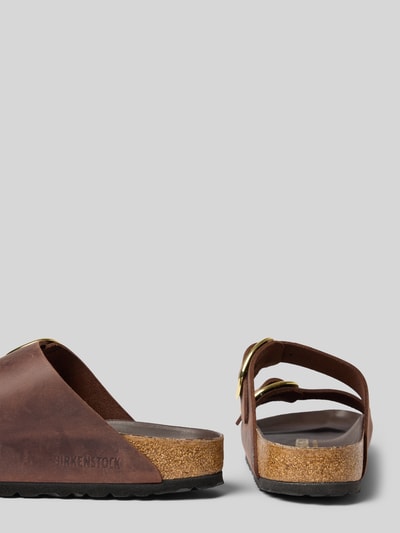 Produktfoto, Slides aus echtem Leder Modell 'Arizona' von Birkenstock, braun, breite metallic Dornschließen, profilierte Sohle, offenes Design, abgerundete Form, flacher 4 cm Absatz, Strukturmix aus glattem Leder und Kork.