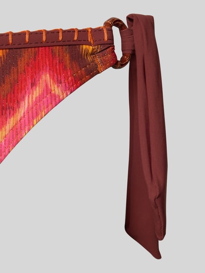 Productfoto, Bikini-Slip met labeldetail model 'SIMA' van Banana Moon in rood met oranje patroonkleur, metalen ring en zijknoopsluiting, materiaalmix met metaal, aansluitende pasvorm