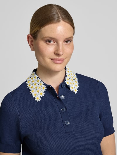 Frauenmodel trägt Regular Fit Poloshirt aus Viskose-Mix Modell 'JAMBER' von Essentiel Antwerp in Dunkelblau mit Blumenkragen, Nahaufnahme Oberkörper.