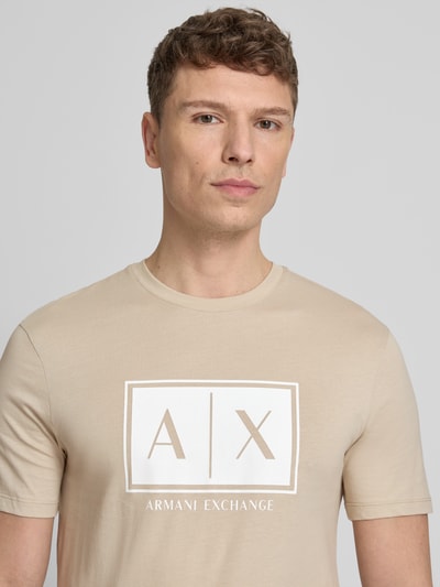 Männermodel trägt T-Shirt mit Logo und Rundhalsausschnitt von ARMANI EXCHANGE in Beige aus Reine Baumwolle, Regular-Fit, Nahaufnahme Oberkörper. Rückenlänge bei Größe M: 71 cm.