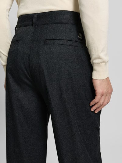 Männermodel trägt Weite Hose mit Viskose-Anteil Modell 'RIKO261' von HUGO in unifarbener Melange-Twill-Optik, Detailaufnahme Rückansicht.