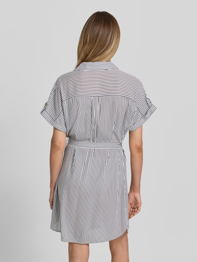 Frauenmodel trägt fließendes Freizeitkleid aus reiner Viskose Modell 'BUMPY' von Vero Moda, jednokolorowy, krótki rękaw, popelina, długość mini, z guzikami i pasem na plecach, Ganzkörperansicht Rückansicht.