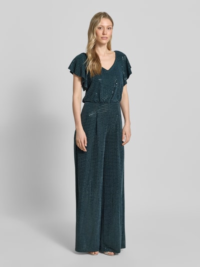 Modelka kobieca ma na sobie 'Schimmernder Jumpsuit mit V-Ausschnitt' od Vera Mont, materiał z dodatkiem stretchu, krój regular fit, połyskująca powierzchnia, dekolt V, zamek z tyłu, długość tyłu w rozmiarze 36: 149 cm, szerokość w rozmiarze 36: 33 cm, długość rękawa w rozmiarze 36: 17 cm, całkowita długość w rozmiarze 36: 153 cm, długość nogawki od wewnątrz w rozmiarze 36: 83 cm, ciemnoniebieskie odcienie, lekki połysk, faktura gładka, pełny widok od przodu