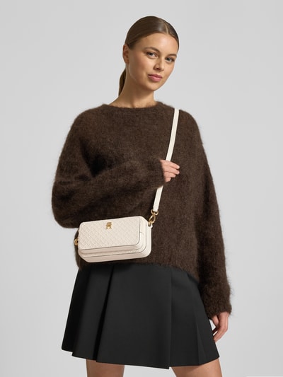 Frauenmodel trägt Umhängetasche mit abnehmbarem Schulterriemen von Tommy Hilfiger, unifarben, Logo-Prägung, Hauptfach, Nahaufnahme Oberkörper.