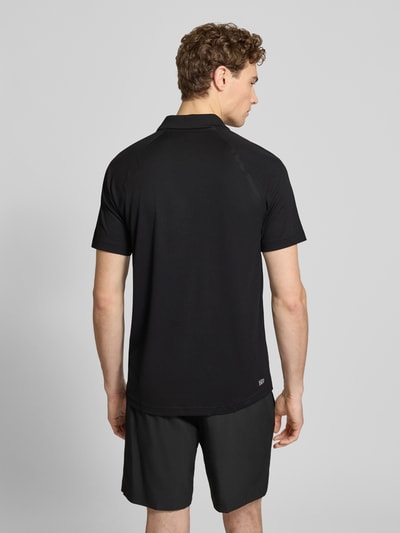 Männermodel trägt Regular Fit Sport Poloshirt mit Label Patch von Lacoste Sport in Schwarz, Piqué-Material, unifarben, Ganzkörperansicht Rückansicht.