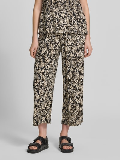 Frauenmodel trägt Straight Fit Stoffhose aus reiner Viskose-Mix Modell 'Faye' von Soyaconcept mit floraler Allover-Print, verkürzte Passform und elastischem Bund mit Tunnelzug, Farbe Beige und Schwarz, glatte Textur, Damen Stoffhose, Ganzkörperansicht von vorne.