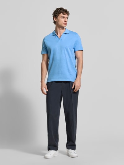 Męski model nosi Slim Fit Poloshirt mit V-Ausschnitt od MCNEAL z bawełny, kołnierzyk polo, krój slim fit, długość tyłu 68 cm w rozmiarze M, zdjęcie całopostaciowe z przodu.