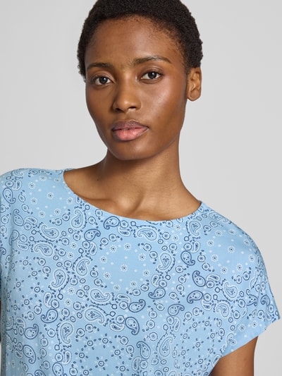Frauenmodel trägt Relaxed Fit T-Shirt aus Viskose-Mix von s.Oliver RED LABEL in Hellblau mit Paisley-Muster, Nahaufnahme Oberkörper.