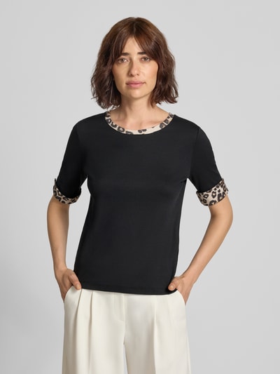 Frauenmodel trägt Regular Fit T-Shirt mit Animal-Print von Marc Cain, schwarz mit gemusterten Details, elastischer Baumwoll-Mix, Nahaufnahme Oberkörper.