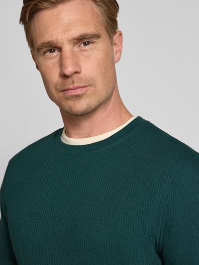 Männermodel trägt Longsleeve mit Ripp-Struktur von MCNEAL in Dunkelgrün, reine Baumwolle, Rundhalsausschnitt, Nahaufnahme Oberkörper. Modell 'MORO'.