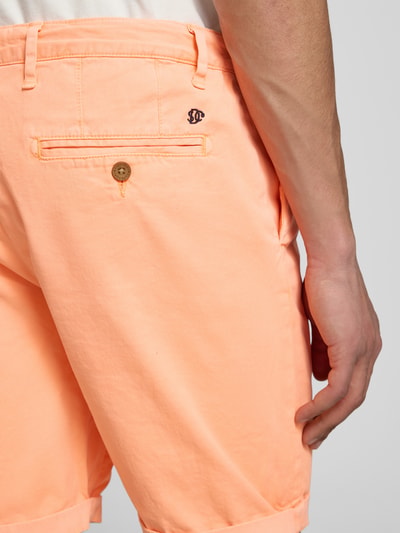 Männermodel trägt Regular Fit Shorts mit Münztasche von Superdry in Apricot, Baumwoll-Mix, Gesäßtaschen, Knopf-Reißverschluss, Detailaufnahme Rückansicht.