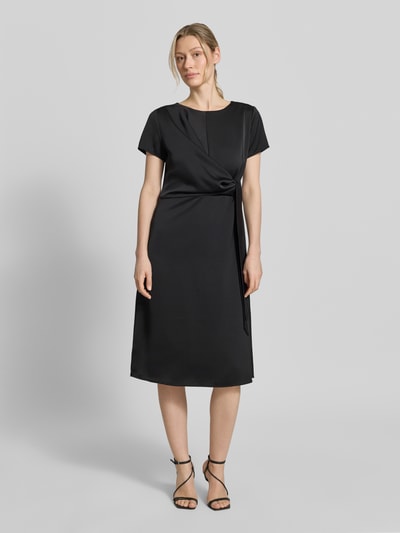 Frauenmodel trägt Knielanges Cocktailkleid mit Knotendetail und Reißverschluss von Rinascimento in Schwarz, Taillierter Schnitt, Rundhalsausschnitt, Knielänge, Rückenlänge bei Größe S 105 cm, Brustweite bei Größe S 46 cm, Ärmellänge bei Größe S 17 cm, glatte Oberfläche, Ganzkörperansicht von vorne.