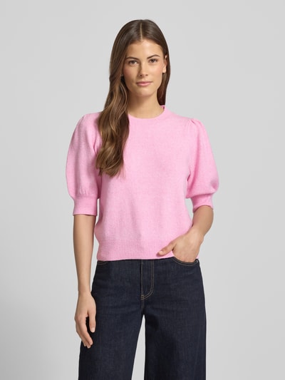 Frauenmodel trägt Regular Fit Strickpullover mit Crew Neck Modell 'DOFFY' von Vero Moda in Rosa, unifarbene Strickoptik, gerippte Abschlüsse, Label Stitching, Halbarm, Ganzkörperansicht von vorne.