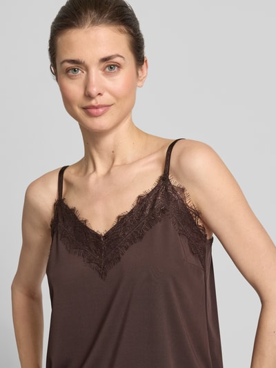 Modelka kobieta nosi Regular Fit Top mit Spitzenbesatz Modell 'Bicco' od FREE/QUENT, elastyczna mieszanka materiałów, krój regular fit, koronkowe wykończenie, ramiączka spaghetti, dekolt w serek, długość pleców w rozmiarze S 41 cm, kolor brązowy, gładka tekstura. Zbliżenie górnej części ciała z przodu.