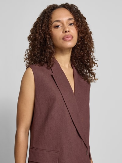 Vrouwenmodel draagt Regular Fit bodywarmer uit mix van linnen en viscose model 'JANKANIA' van BOSS, melangelook twill, reverskraag, 1-knoopsluiting, zijdelingse rompzoom, klepzakken, materiaalverwerking twill. Close-up bovenlichaam.