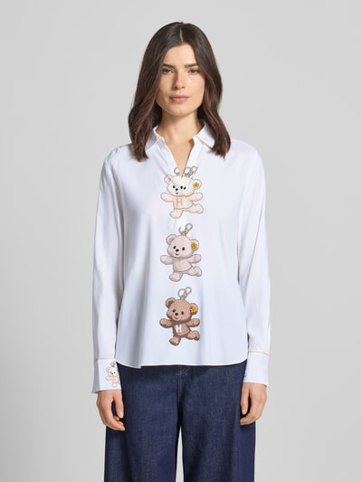 Kobiece model nosi Bluse aus Seiden-Mix mit Motiv-Print von HERZENS, mieszanka jedwabiu z dodatkiem streczu, krój loose fit, kołnierzyk koszulowy, dekolt w serek, nadruk z motywem, wydłużony tył, zaokrąglony dół, długość tyłu w rozmiarze 36: 69 cm, długość rękawów w rozmiarze 36: 60 cm, jasne kolory, motyw misi, gładka tekstura, widok całej sylwetki z przodu.