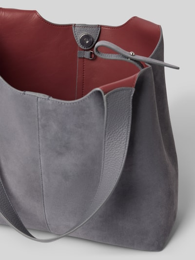 Produktfoto, Tote Bag mit Logo-Detail von Coccinelle in Grau mit roter Innenseite, weiche Wildleder-Textur, Magnetverschluss, Schulterriemen, herausnehmbare Innentasche, Maße: 36x29x12 cm, Schulterriemen 54 cm.