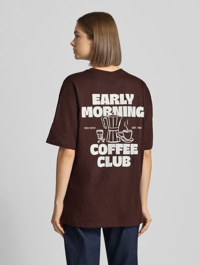 Frauenmodel trägt Oversized Fit T-Shirt aus reiner Baumwolle mit Label-Detail von REVIEW, dunkelbraun mit Print auf dem Rücken, Ganzkörperansicht Rückansicht.