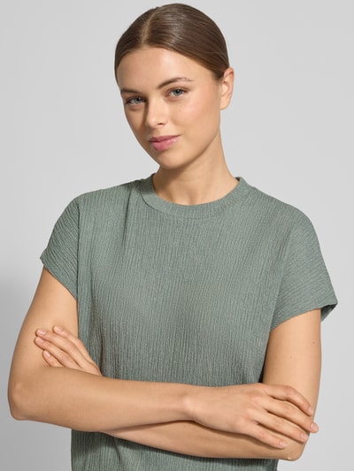 Vrouwenmodel draagt T-shirt met structuurpatroon en ronde hals van Christian Berg Woman, materiaalmix met viscose, regular fit, Nahaufnahme Oberkörper.