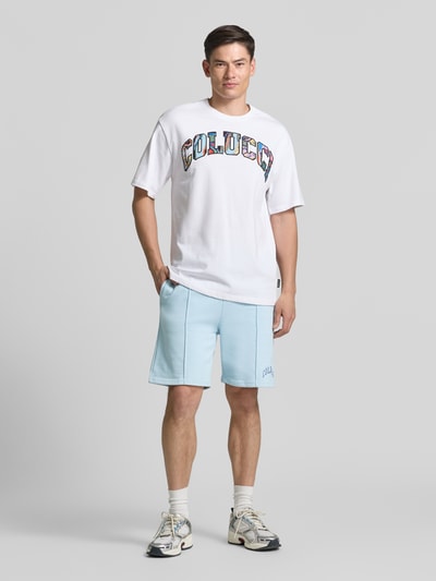 Männermodel trägt Regular Fit Shorts mit Tunnelzug von COLUCCI aus reiner Baumwolle mit Label-Stitching, hellblau, Ganzkörperansicht von vorne.