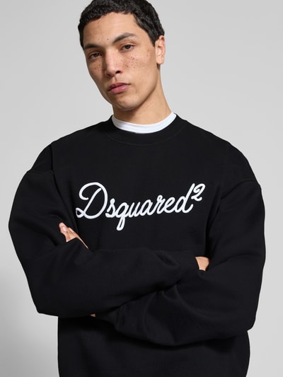 Männermodel trägt Sweatshirt aus reiner Baumwolle von Dsquared2 in Schwarz mit Label-Detail, Relaxed-Fit, elastische Abschlüsse, Nahaufnahme Oberkörper.