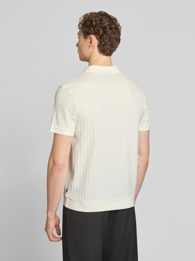 Männermodel trägt Regular Fit Poloshirt mit V-Ausschnitt Modell 'Baronito' von JOOP! Collection in Creme mit Strukturmuster, Ganzkörperansicht Rückansicht.