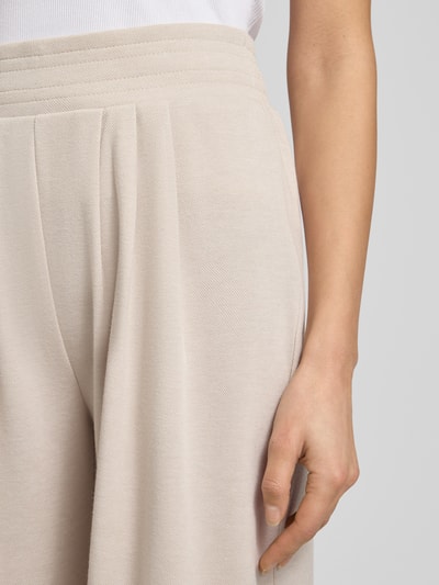Kobiece model prezentuje Wide Fit Stoffhose mit gelegten Falten von Christian Berg Woman, mieszanka bawełny, elastyczny pas, jasny beż, wyraźna struktura materiału, detal pasa i plisy, zbliżenie na biodro.