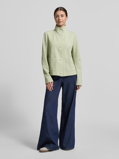 Modelka nosi Regular Fit Jacke mit Stehkragen od WHITE LABEL, jasna zieleń, bawełniany elastyczny materiał, kieszenie naszyte, guziki, długość tyłu w rozmiarze 36: 57 cm, szerokość w rozmiarze 36: 50 cm, długość rękawa w rozmiarze 36: 65 cm; widok całej sylwetki z przodu.