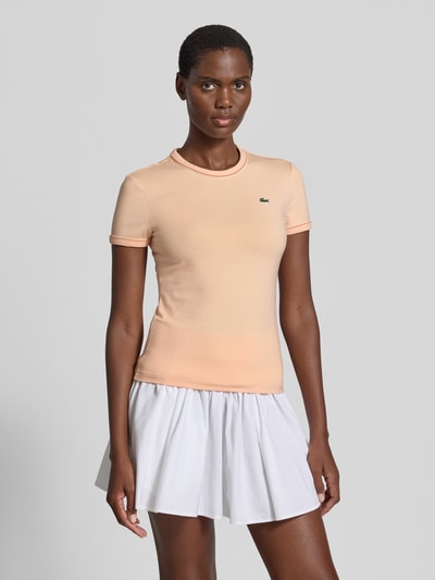 Frauenmodel trägt Slim Fit T-Shirt aus Baumwoll-Mix von Lacoste in Apricot, unifarben, Logo-Stitching, Kontrastpaspel, Ganzkörperansicht von vorne.