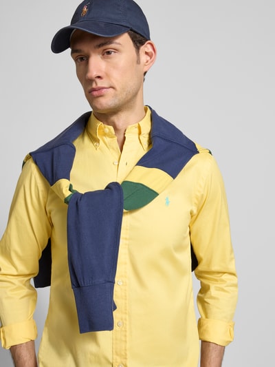 Männermodel trägt Regular Fit Freizeithemd aus reiner Baumwolle von Polo Ralph Lauren in Gelb, mit Knopfleiste und Logo-Stitching, Nahaufnahme Oberkörper.