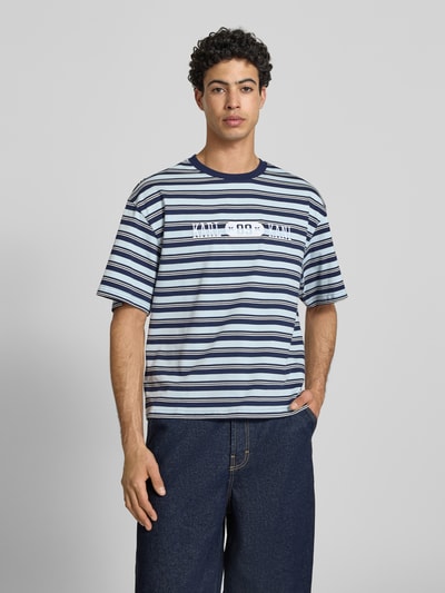 Männermodel trägt Regular Fit T-Shirt mit Logo-Stitching von KARL KANI, Streifenmuster, Reine Baumwolle, Rundhalsausschnitt, Ganzkörperansicht von vorne.