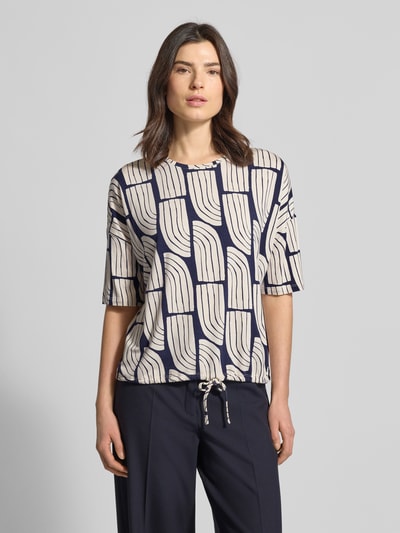 Vrouwenmodel draagt T-Shirt aus Viskose-Elasthan-Mix im Allover-Look van Christian Berg Woman, relaxed fit, ronde hals, tunnelkoord, viscose-elastanmix in blauw-beige, voorkant, bovenlichaam close-up.