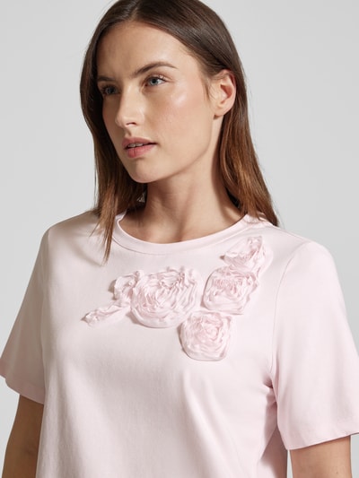 Frauenmodel trägt Regular Fit T-Shirt mit floralem Besatz von Christian Berg Woman Selection, zartrosafarbener Baumwoll-Mix, Nahaufnahme Oberkörper.