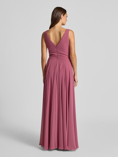 Frauenmodel trägt Abendkleid mit V-Ausschnitt von TROYDEN COLLECTION, A-Linie, Maxikleid, Reißverschluss auf der Rückseite, Rückenlänge 155 cm, Brustweite 43 cm, mattrosa Stoff, fließende Textur, Ganzkörperansicht Rückansicht.