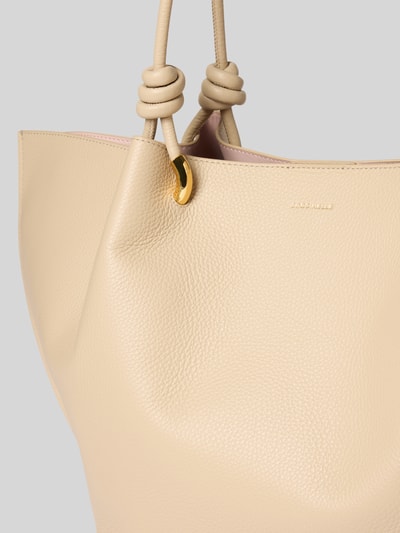 Produktfoto, Shopper mit Label-Detail Modell 'FINN' von Coccinelle in Beige mit goldfarbenem Element, grobe Ledertextur, Kontext: Damen Shopper, Hauptfach mit Druckknopfverschluss, lange Tragegriffe, zusätzliche Reißverschlusstasche, Maße: 56x33x17 cm, Schulterriemenlänge 68 cm