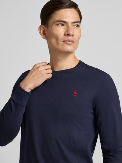 Męski model nosi Custom Slim Fit Longsleeve mit Label-Stitching od Polo Ralph Lauren z bawełny, okrągły dekolt, kolor granatowy, długość tyłu 70 cm, rozmiar M, wyhaftowane logo, zbliżenie na górną część ciała.