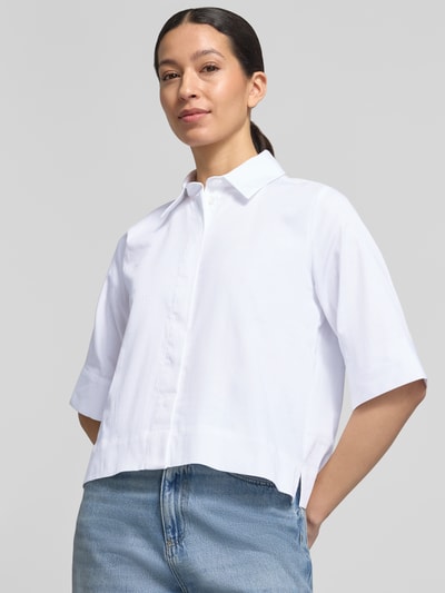 Modelka kobieca nosi Boxy Fit Bluse mit verdeckter Knopfleiste od Milano Italy, biały bawełniany materiał ze stretchem, kołnierzyk koszulowy, długość tyłu 54 cm, długość rękawa 34 cm, widok na górną część ciała z przodu.