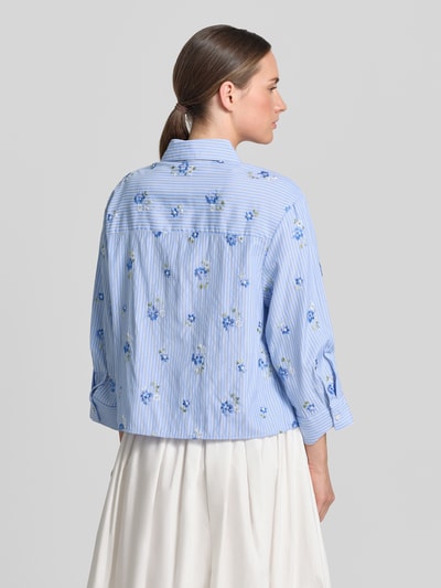 Frauenmodel trägt Hemdbluse mit Knopfleiste Modell 'FLORIX' von Mango im Material-Mix mit Viskose-Anteil, Regular-Fit, Rückenlänge 49 cm, Ärmellänge 46 cm, Hemdblusenkragen, blau mit Streifen und Blumen-Muster, Ganzkörperansicht Rückansicht.