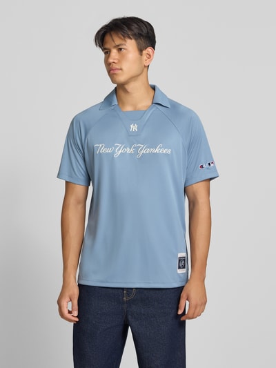 Męski model nosi Relaxed Fit Poloshirt mit Logo-Stitching od Champion, jasnoniebieska koszulka polo z wyhaftowanym logo, krój relaxed fit, kołnierzyk polo, z krótkim rękawem, długość tyłu w rozmiarze M: 70 cm, Ganzkörperansicht von vorne.