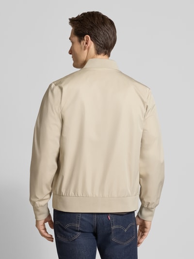 Männermodel trägt beige Bomberjacke mit Reißverschlusstaschen Modell 'MATTE' von CK Calvin Klein, Struktur glatt, Ganzkörperansicht Rückansicht.