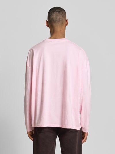 Männermodel trägt Longsleeve mit Logo-Print Modell 'GIXY' von American Vintage in Rosa, Reine Baumwolle, Loose-Fit, Rückenlänge 72 cm, Ganzkörperansicht Rückansicht.