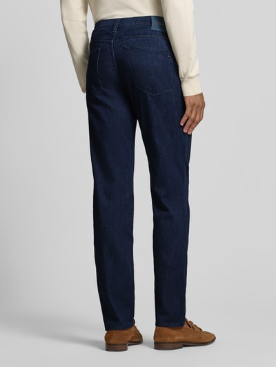 Männermodel trägt Slim Fit Jeans mit Seiden-Anteil Modell 'Chuck' von BRAX in Dunkelblau, 5-Pocket-Design, Ganzkörperansicht Rückansicht. Elastischer Baumwoll-Mix mit Viskose-Seiden-Anteil, Knopf- und Reißverschluss, Bundweite bei Größe 32/32: 44 cm, Innenbeinlänge: 81 cm.